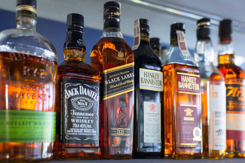 Selection of whiskey bottles on the bar shelf. Selective focus on the Johnnie Walker Black Label bottle.