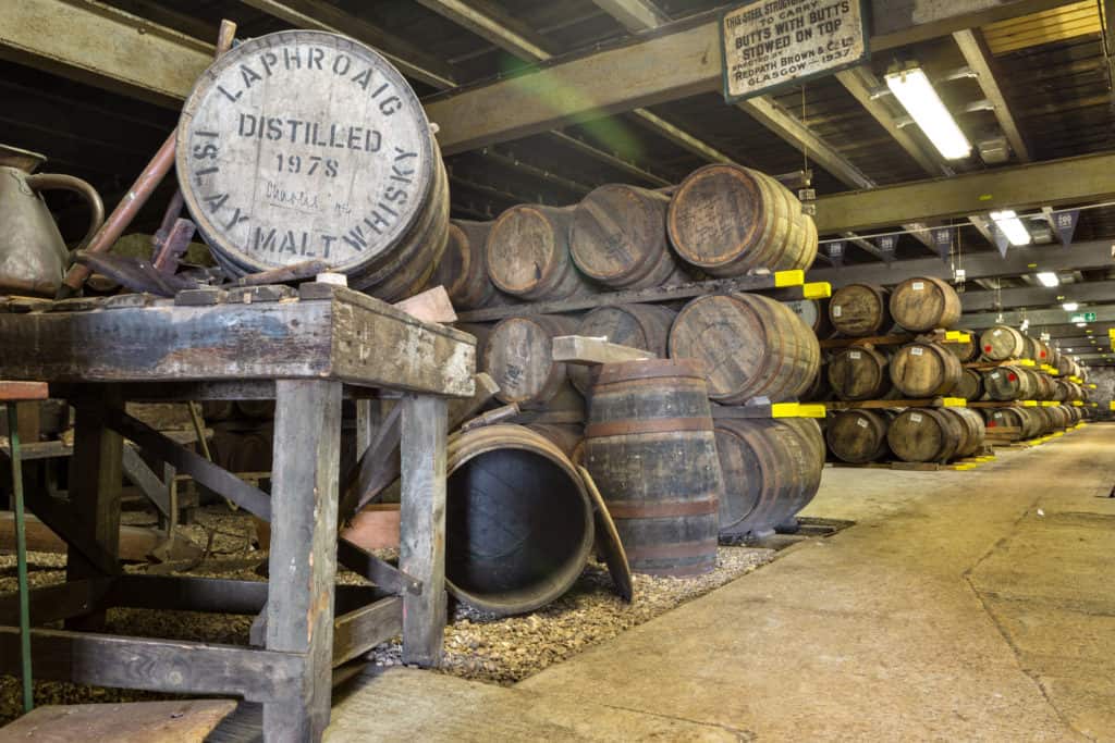 Old wooden barrels and casks at Lafroaig whisky distillery warehouse established in 1815.