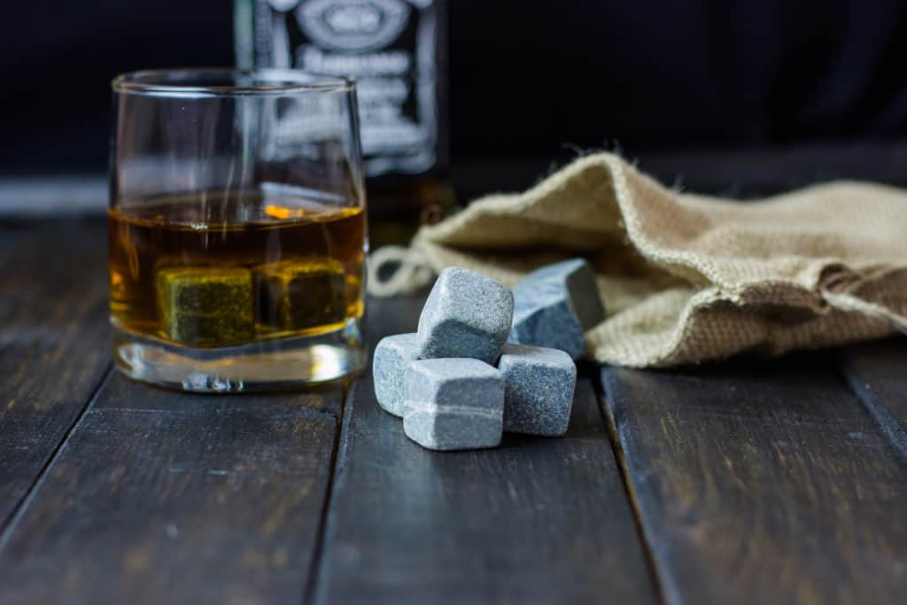 Whiskey in a glass with stones for cooling drinks on a wooden table