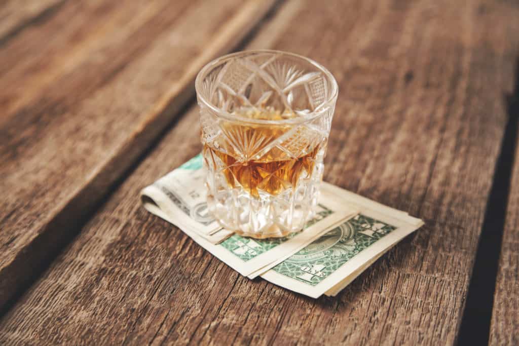 whiskey glass on money onthe wooden desk